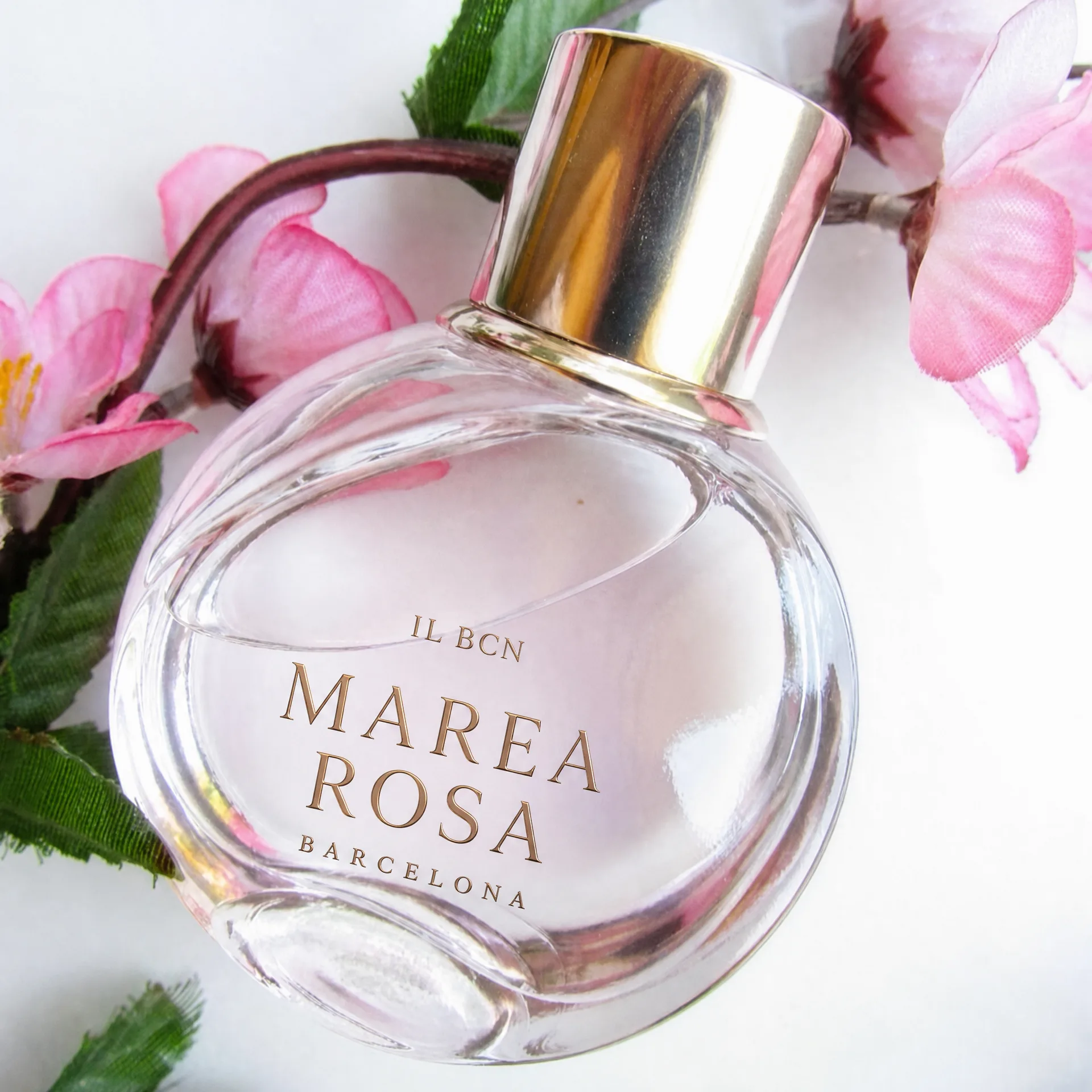 Primer plano del frasco Marea Rosa de IL BCN entre flores rosas